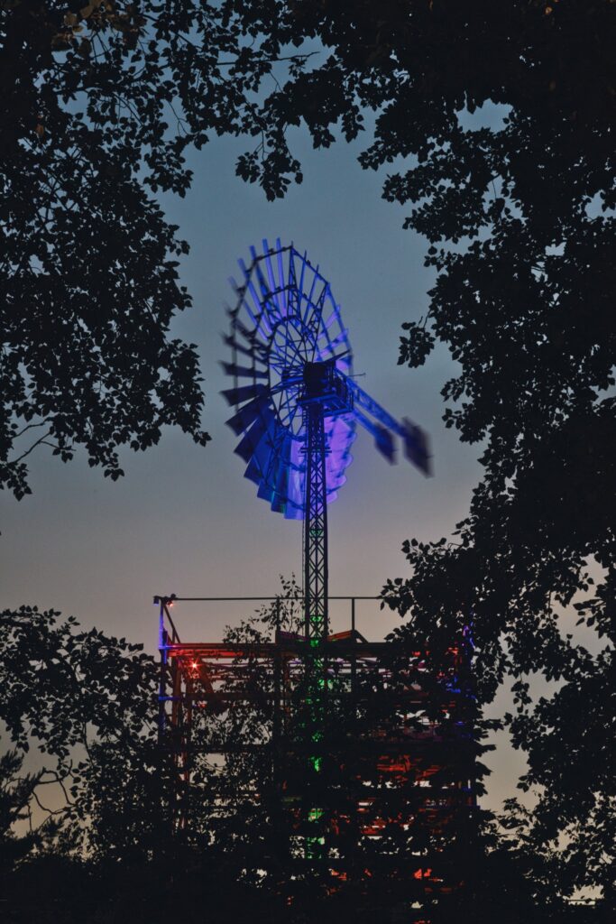 Blau beleuchtetes Windrad mit Stahlgerüst im Landschaftspark Duisburg-Nord am Abend